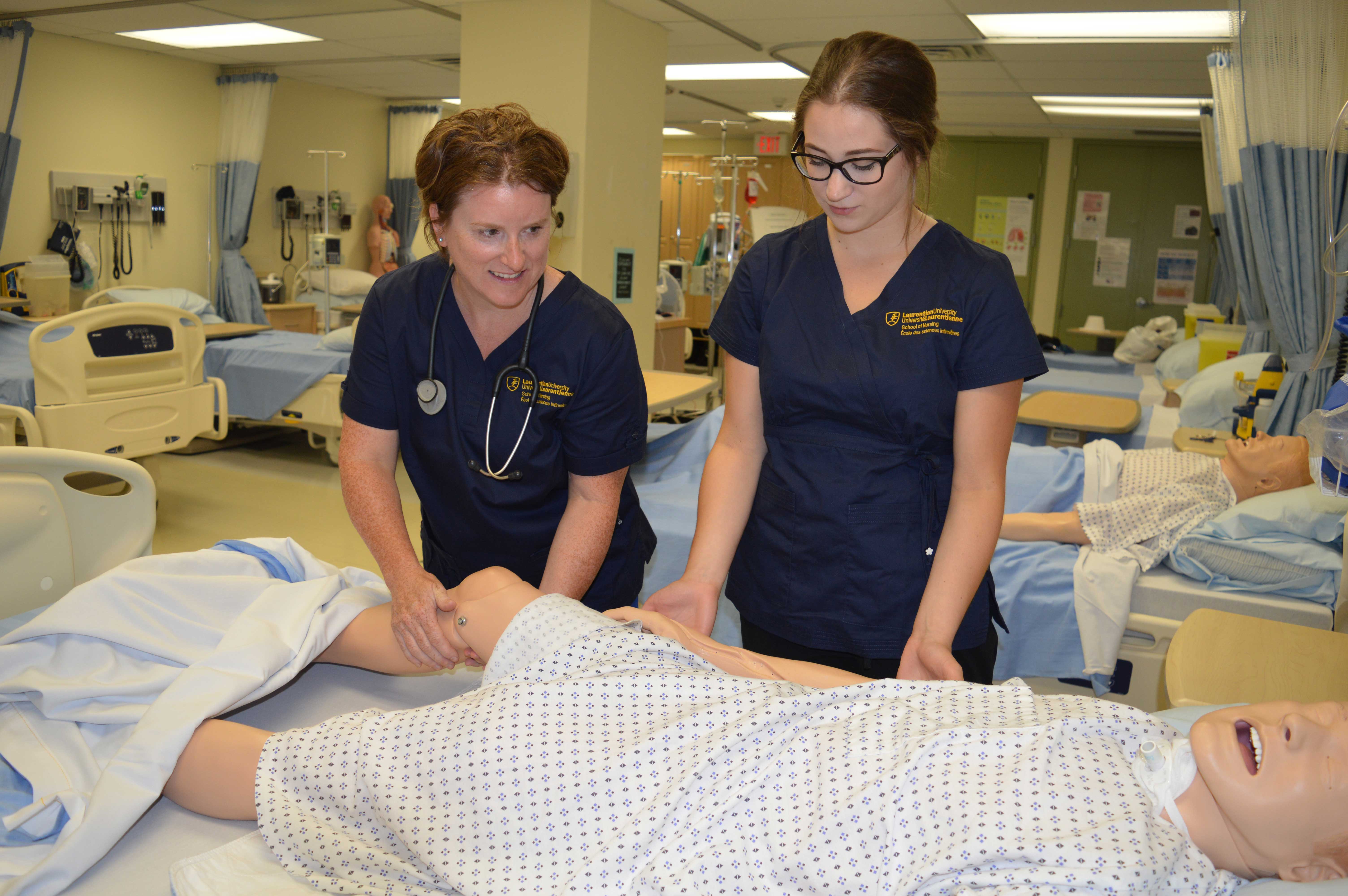 Nursing students working with a dummy in a clinical lab.